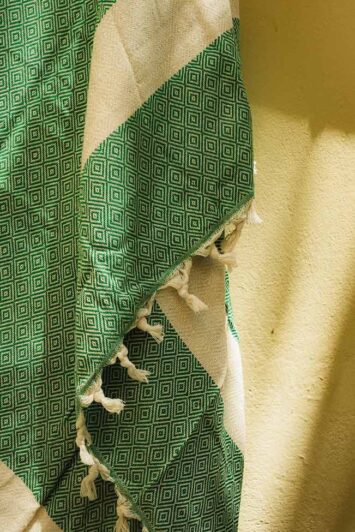 Κοντινή λήψη πράσινης πετσέτας hamam με λευκές ρίγες και κρόσσια