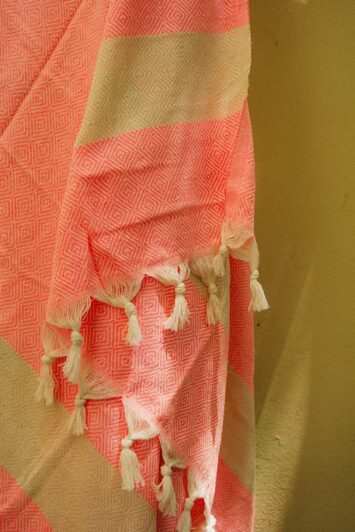 Λεπτομέρεια της ροζ πετσέτας hammam με λευκά κρόσσια και γεωμετρικά σχέδια